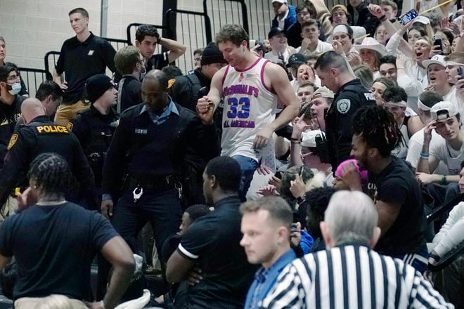 Police remove a fan from the stands after a brawl stopped play during the second half of a Northeast Conference Championship match between Bryant and Wagner.